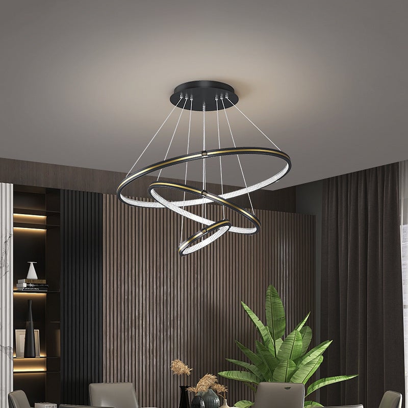 Black Arisha three-ring pendant light in a dining area with a plant