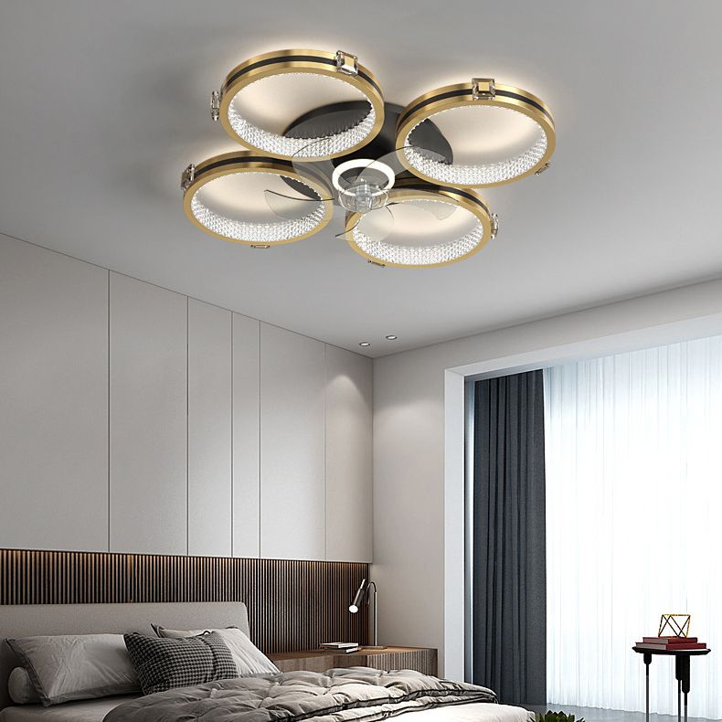 Illuminated Kirsten four-ring ceiling fan light above a bed with a dark headboard