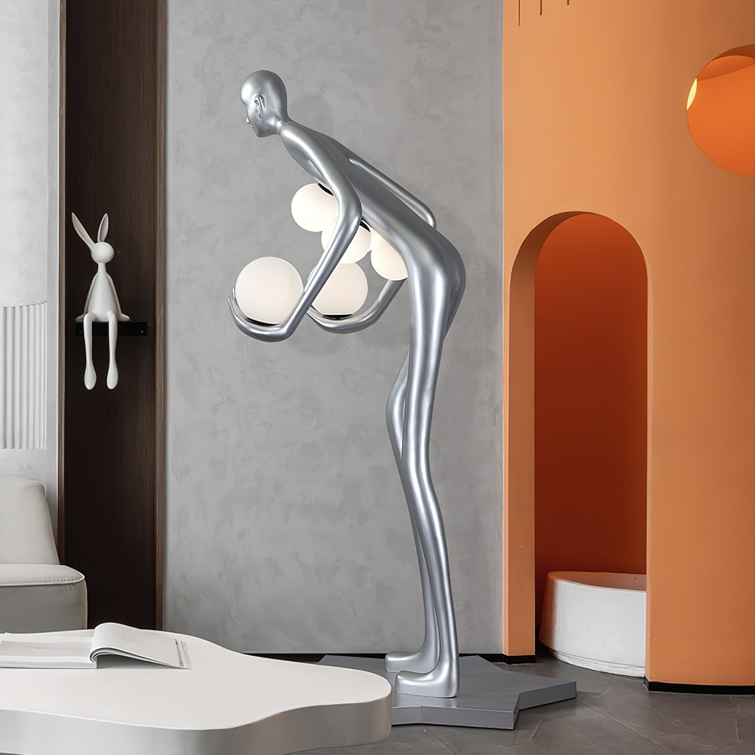 Rear-side view of a silver figure with white globes beside orange niches and a white coffee table