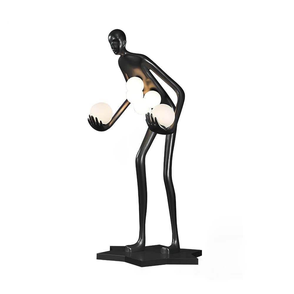 Black human-figure floor lamp cradling white globes on a black star-shaped base