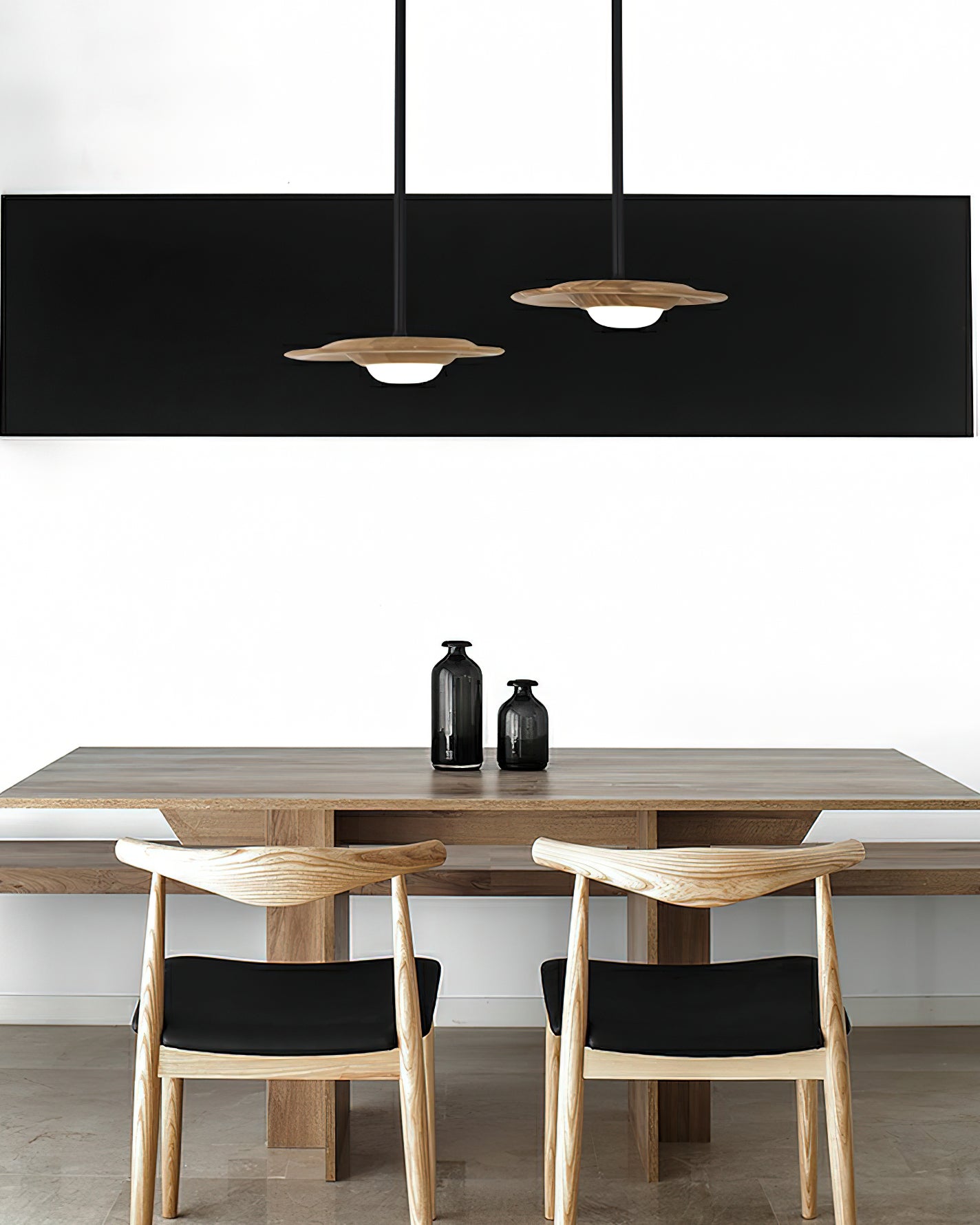 Two light wood-grain pendants over a wood table and chairs, with black rectangular wall art and two dark vases