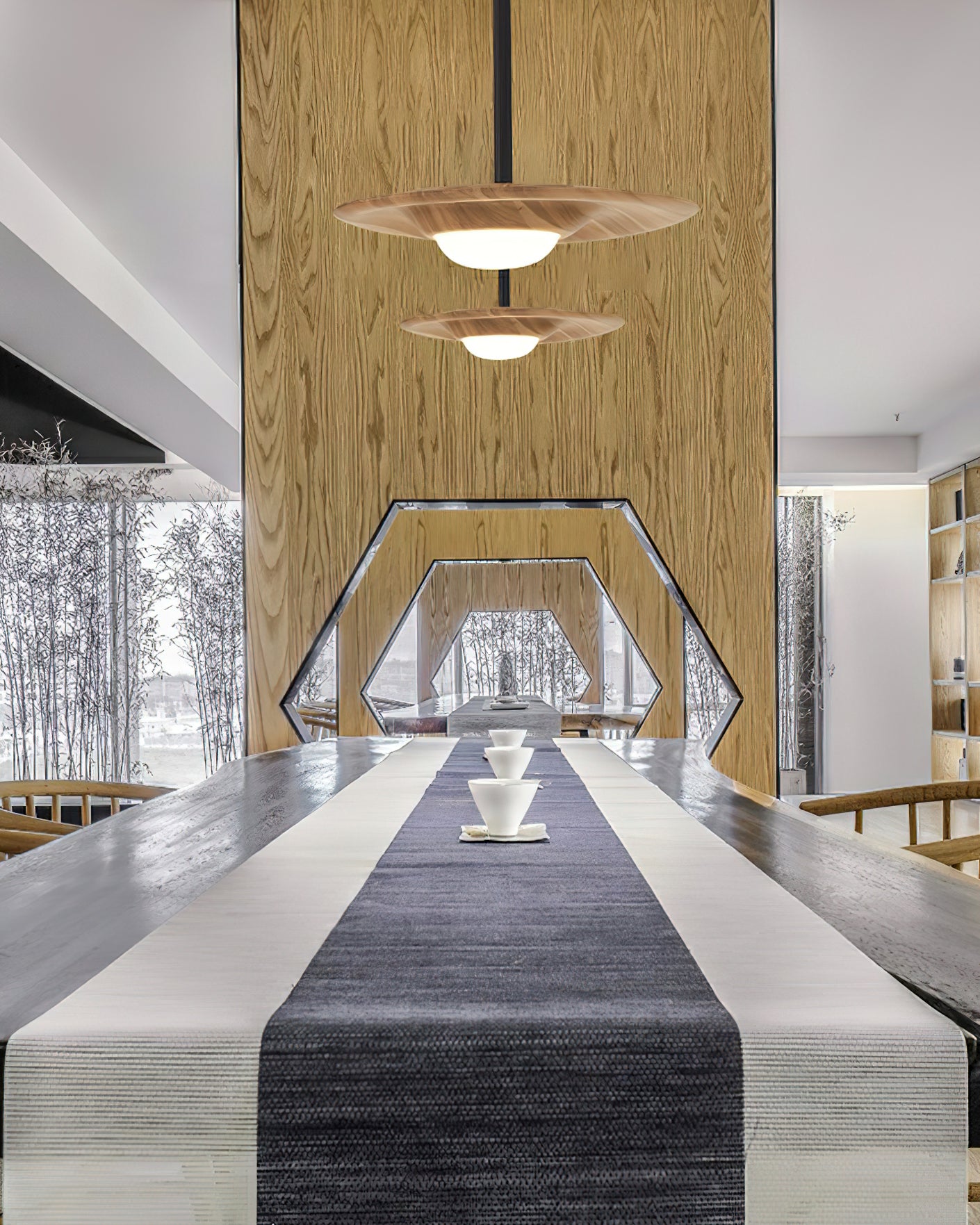 Two light wood-grain pendants over a tea table with cups, beside a tall wood partition with a hexagonal opening