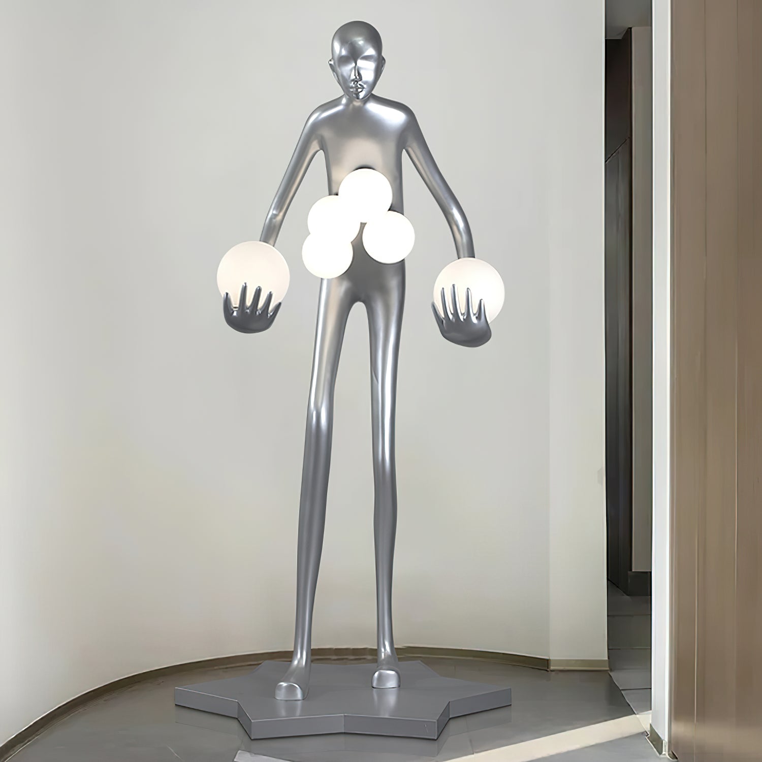 Front view of a silver figure holding six white globes in a curved-wall alcove on gray tile