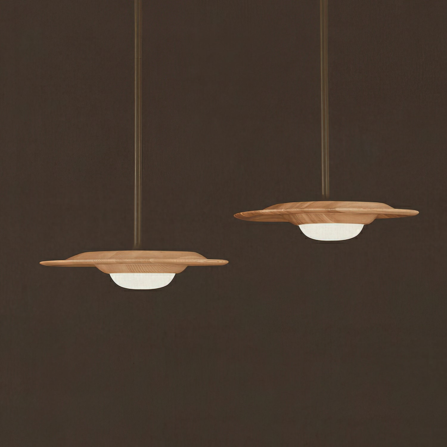 Two light wood-grain disc shades with white glowing diffusers at different drops against a brown background