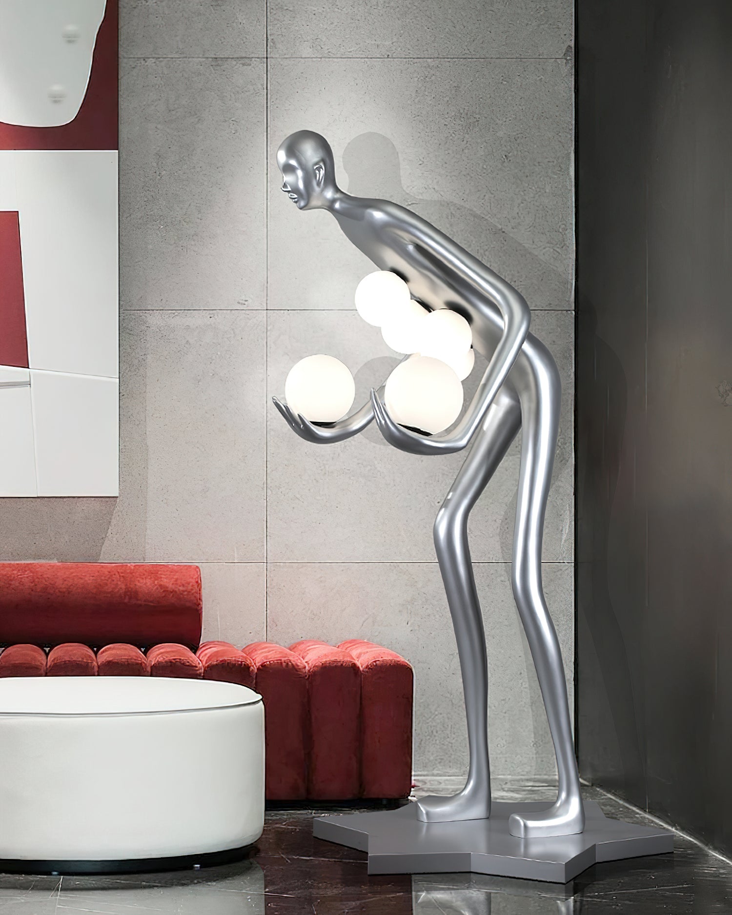 Side view of a silver figure holding white globes beside a red sofa and round white coffee table