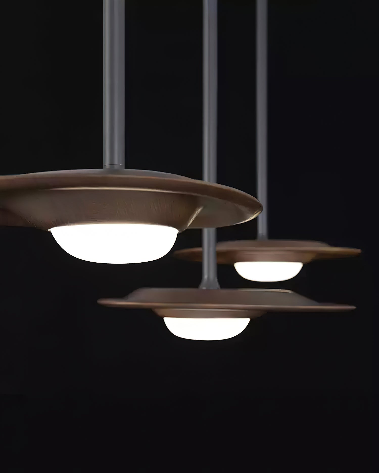 Three dark wood-grain shades with glowing white domes and black rods against a black background