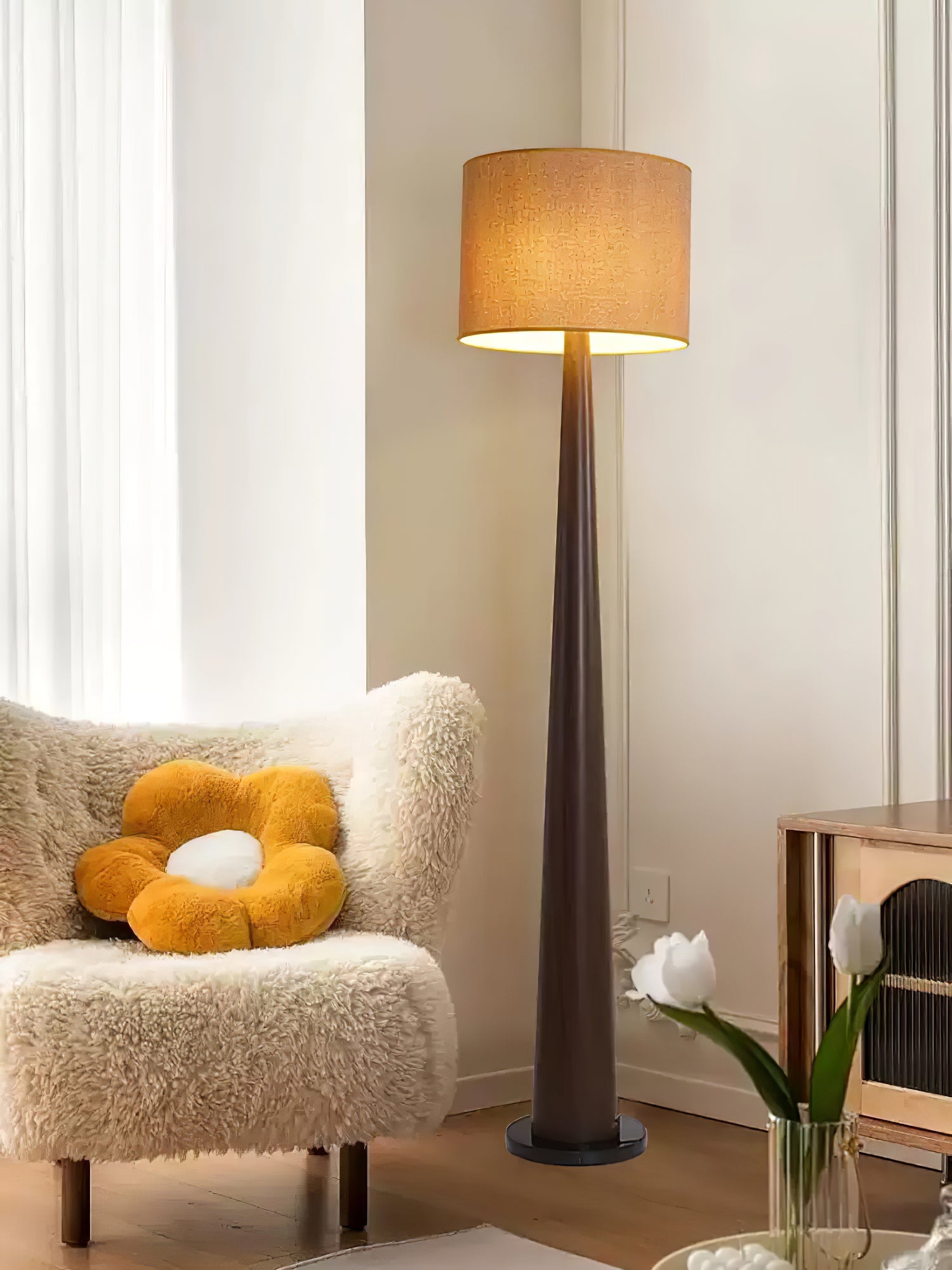 Dark brown floor lamp with a textured warm beige shade beside a cream armchair and yellow flower cushion