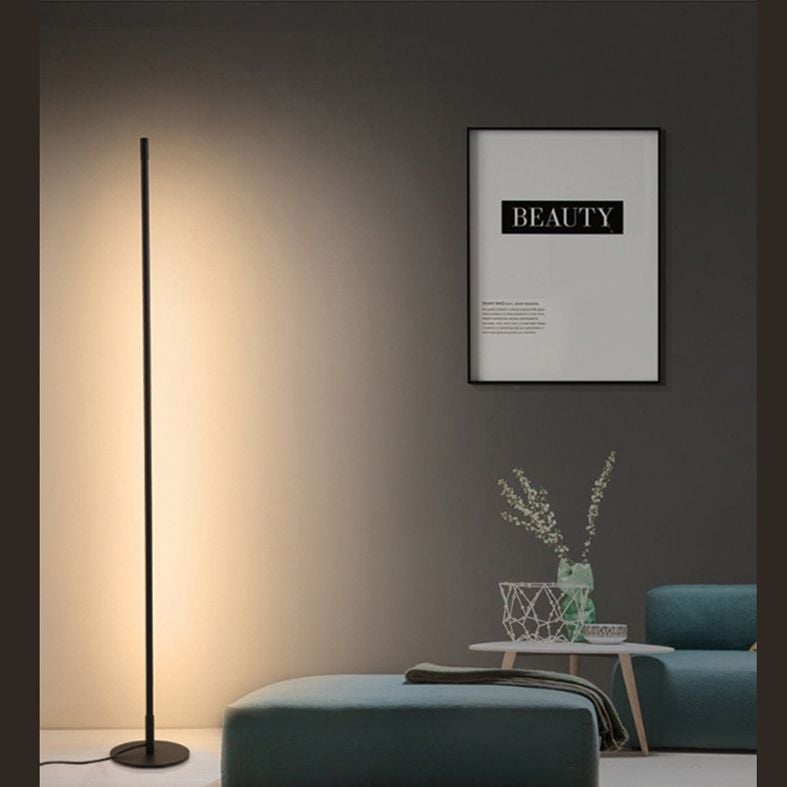 Edge warm floor light beside living-room seating and framed print