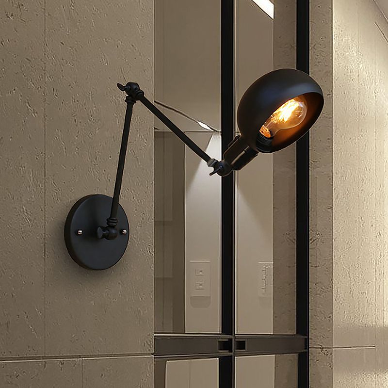 Lit black metal wall lamp beside a framed mirror