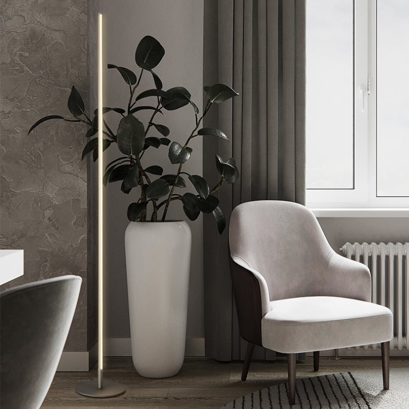 Silver-colour Edge floor lamp beside a pale chair and large potted plant