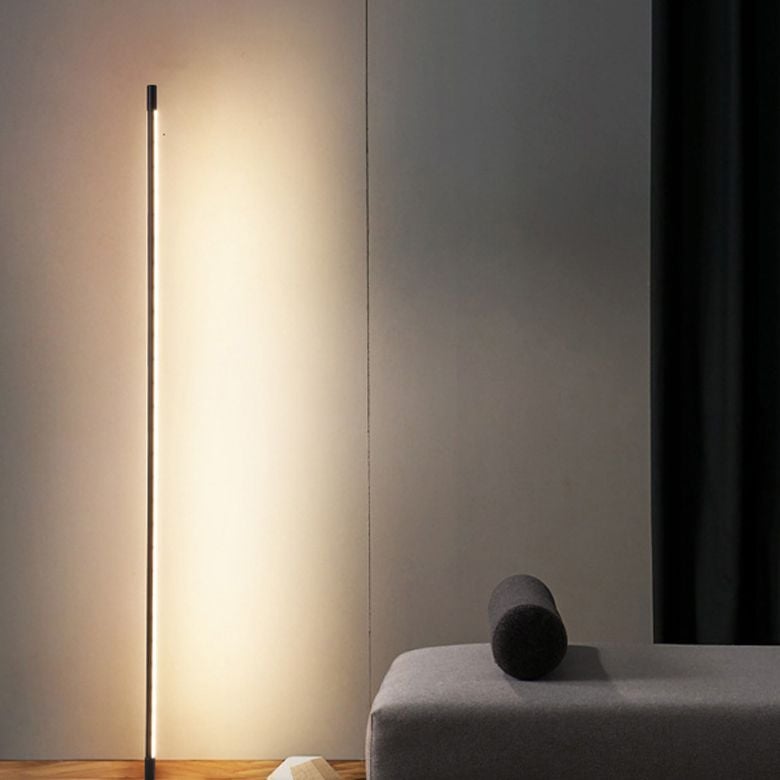 Edge floor light beside a dark sofa and curtain