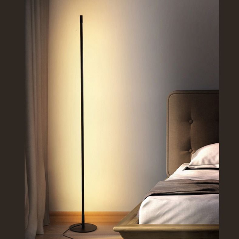 Black Edge floor lamp casting warm light beside a bed