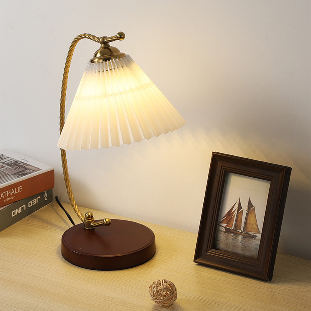 Dotty pleated lamp glowing beside framed sailboat art and books, with a black cord behind the base