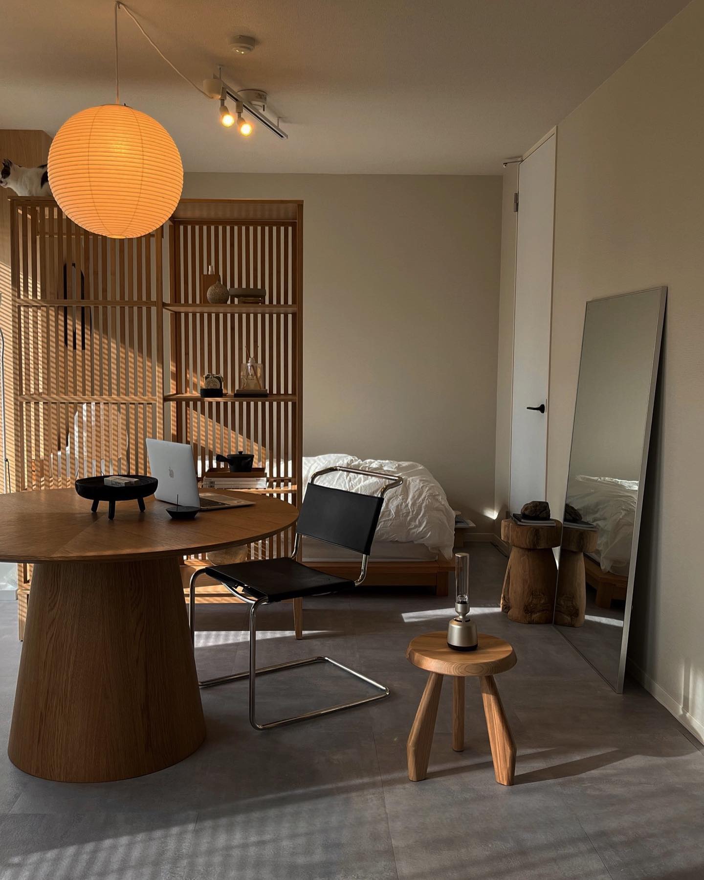 Orange-looking illuminated globe on a looping white cord above a wood desk with laptop and black chair