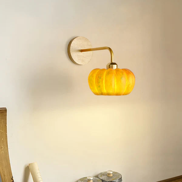 Side view of the yellow lobed shade, gold-tone arm and round grain-patterned wall plate
