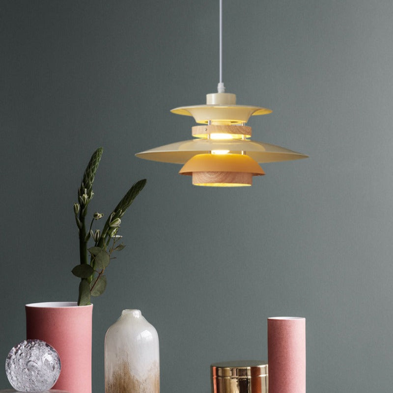 Pale Morandi layered pendant with wood-tone bands above pink, white and gold-tone vases against blue-grey wall