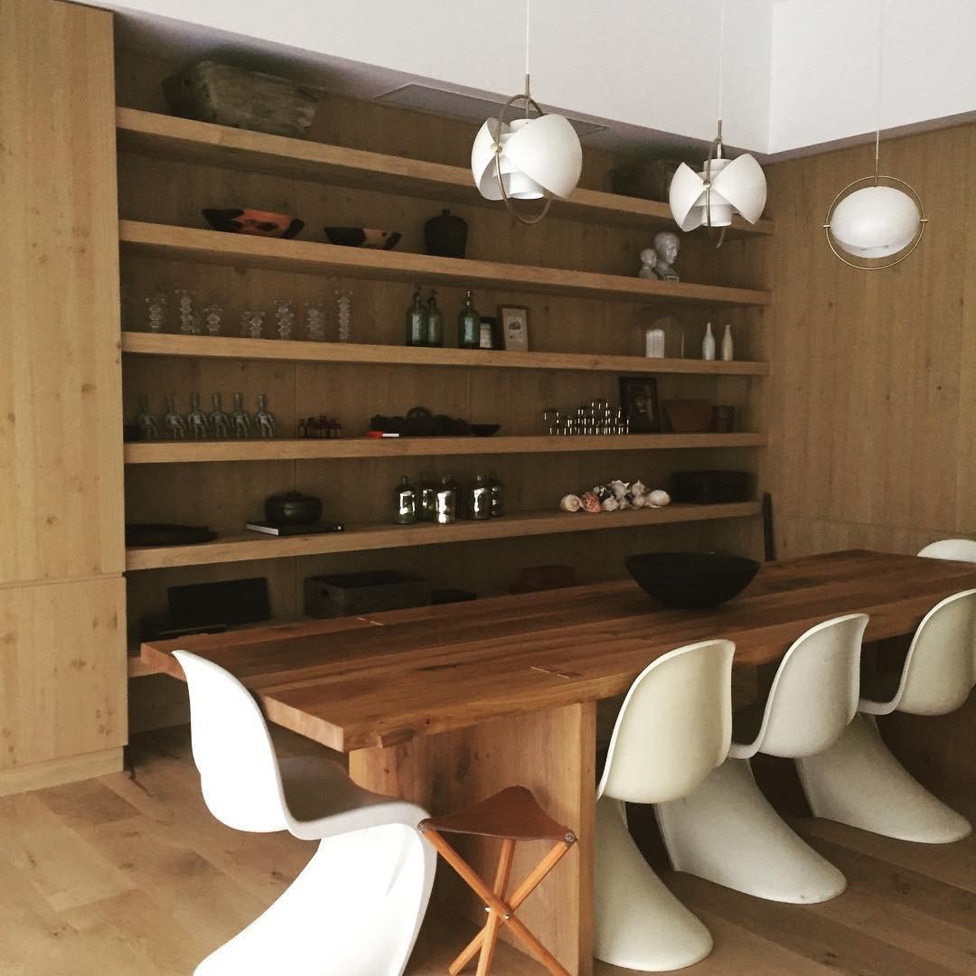 White adjustable ring pendants above a timber dining table and open shelving.