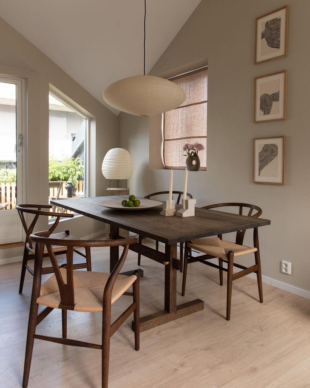 Flattened paper pendant above a dark wood dining table with curved wooden chairs, woven seats and candles