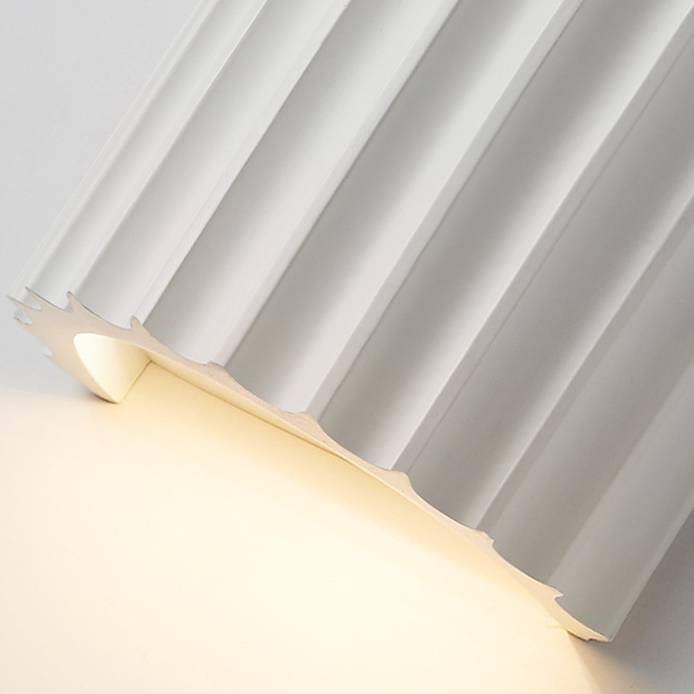 Close underside and vertical flutes of a white curved wall shade with its pale interior visible
