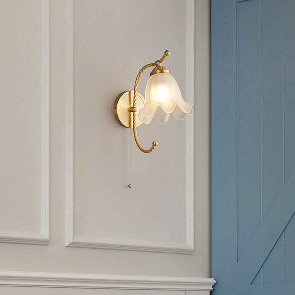 Curled-arm white petal wall light with hanging chain and ball beside cream moulding and blue wall panel