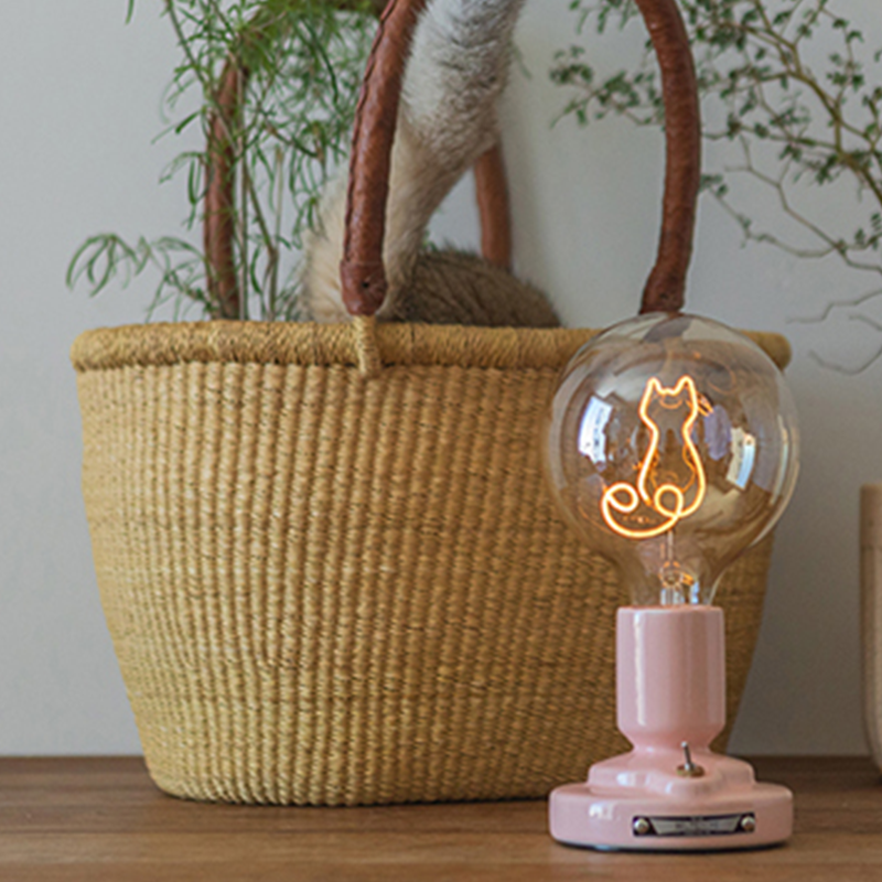 Pink Cat style with pink glossy pedestal and a slender glowing cat outline beside a woven basket and greenery