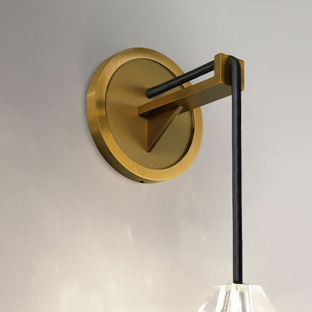 Close-up of gold-tone circular wall plate and projecting bracket with triangular support and black cable