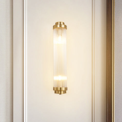 Narrow Gold rod wall light glowing on a cream wall between vertical mouldings near curtain edges