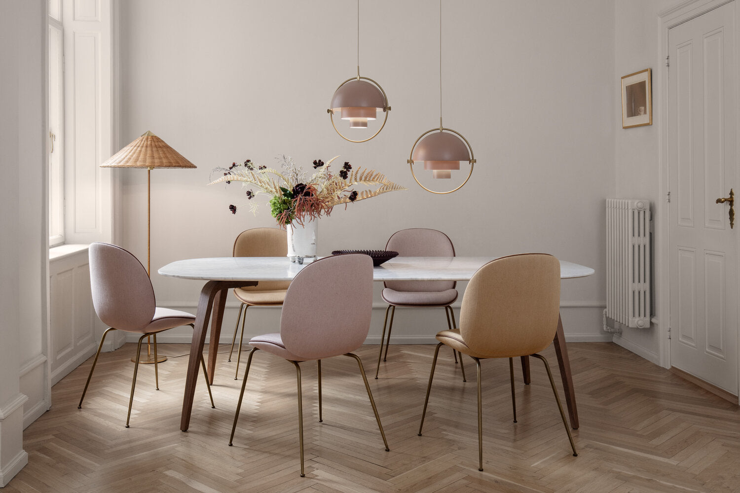 Two pink-toned ring pendants above a table with pastel dining chairs.