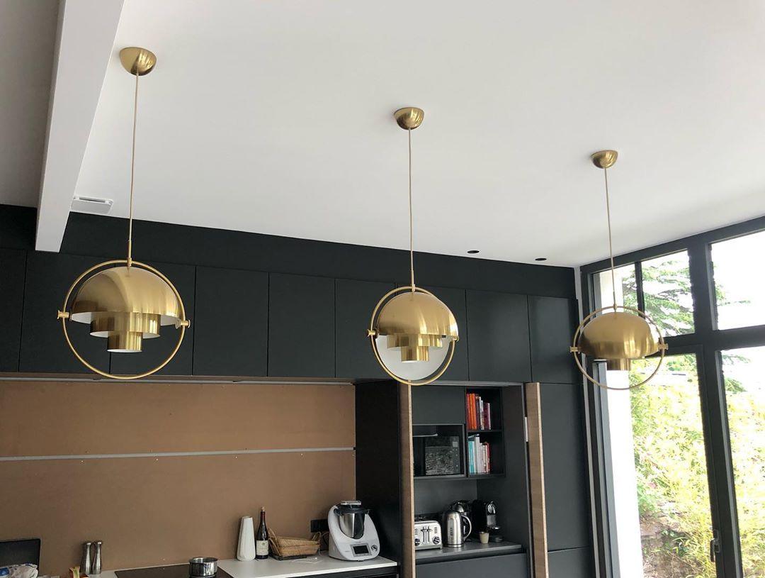 Three gold-toned pendants suspended along a kitchen island.