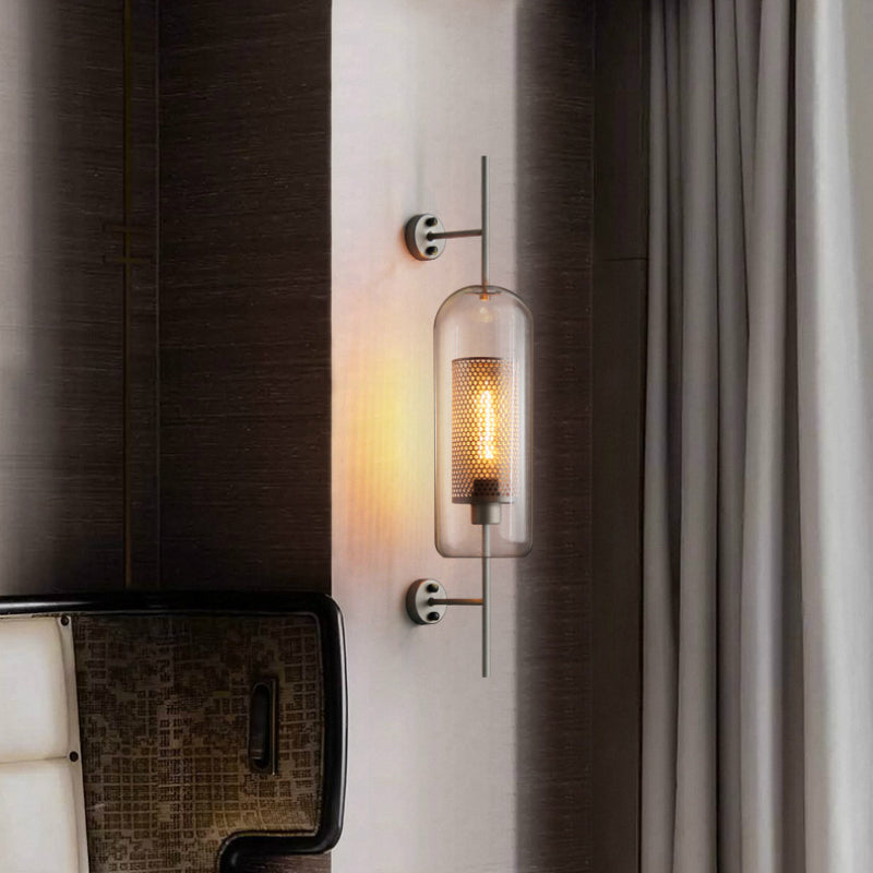 Lit capsule wall sconce between dark wall panels beside gray curtain and woven bench with white cushion