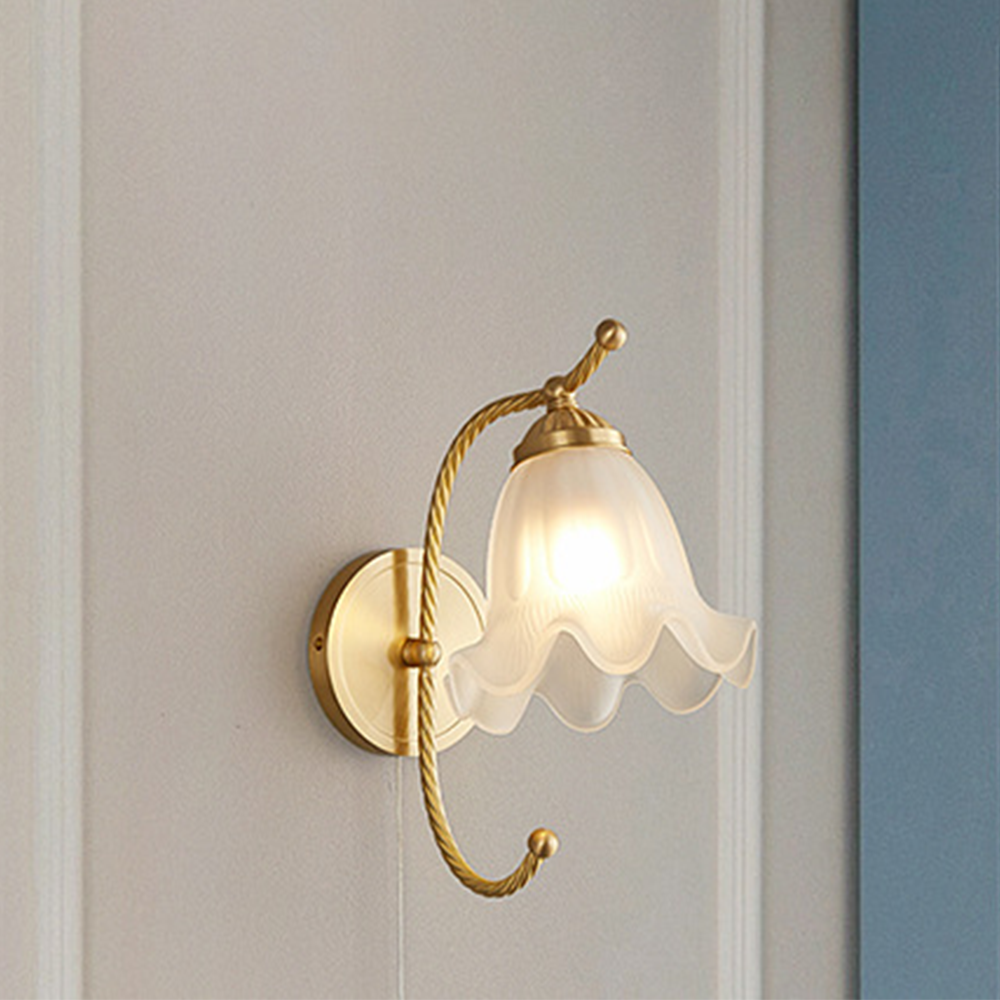 White scalloped bell shade on gold-tone curled arm with ball tips and plain round wallplate beside blue wall panel
