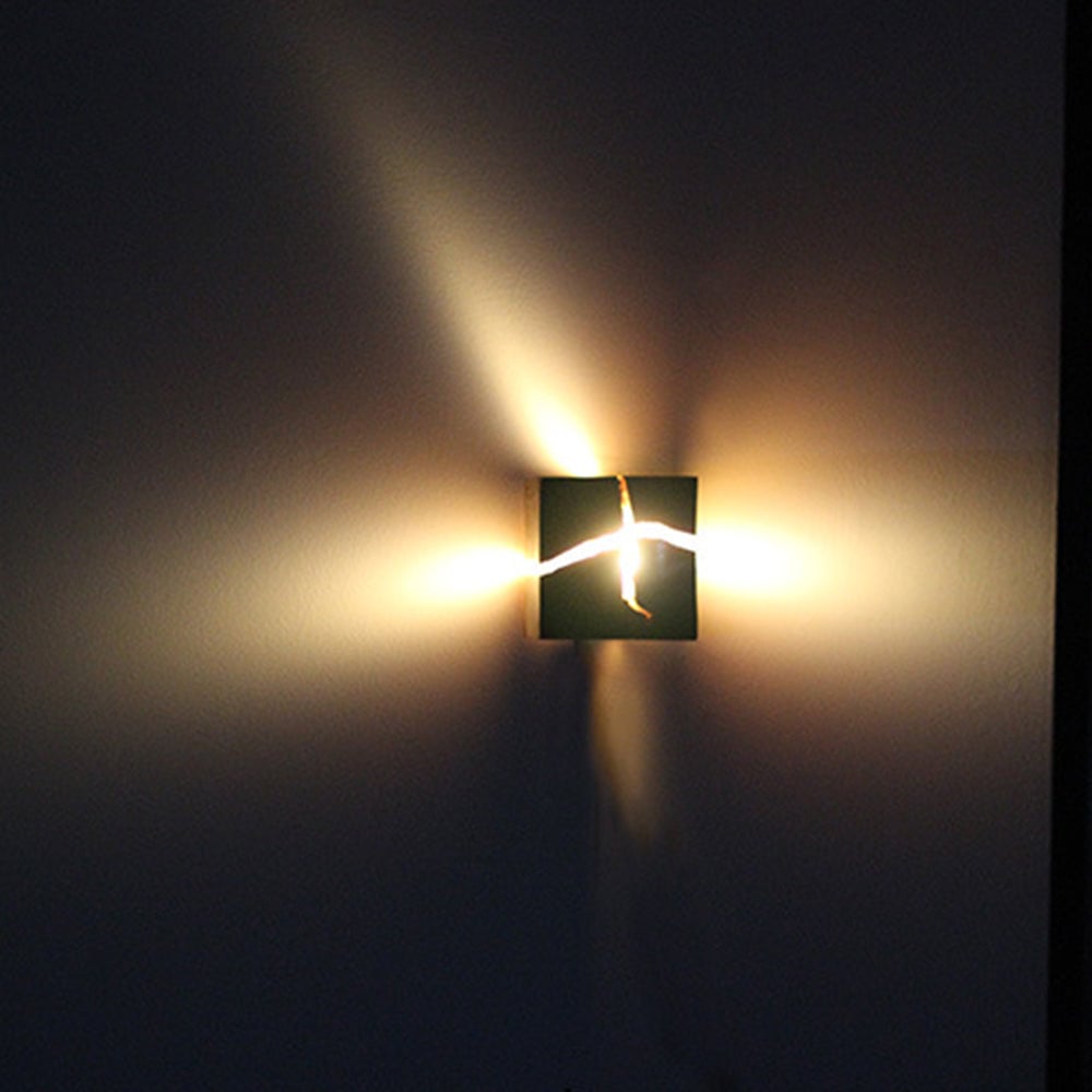 Distant front view of glowing crack-pattern wood wall light casting fan-like patches on a dark wall