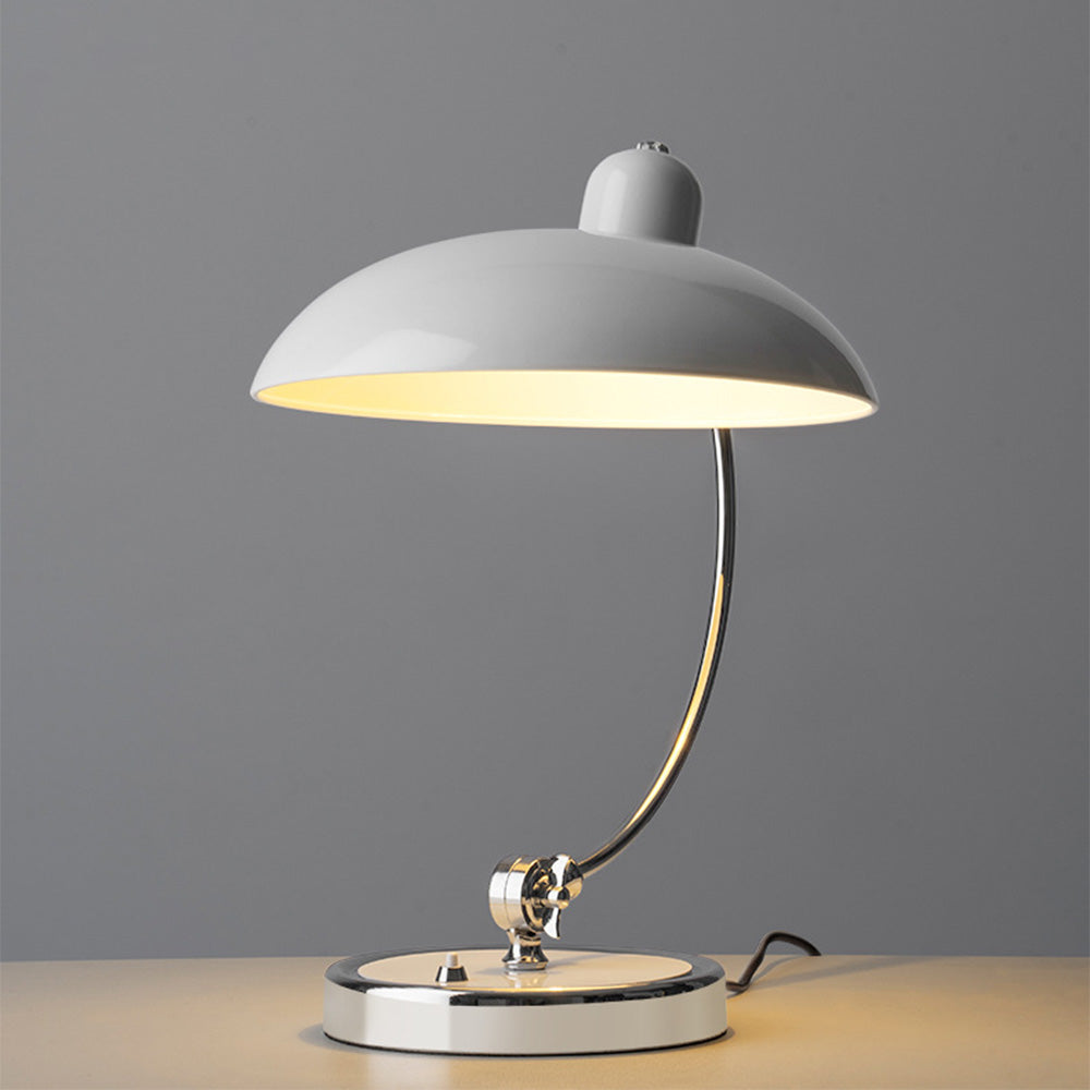 Lit white dome table lamp with curved reflective stem and pale round base against a gray backdrop