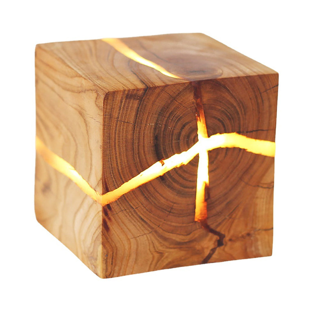 Close-up of illuminated cracks across a wood-grain cube