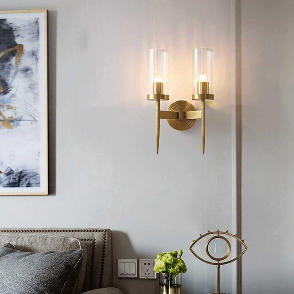 Double-arm ribbed wall light above a bedside table with flowers and an eye-shaped mirror beside framed art