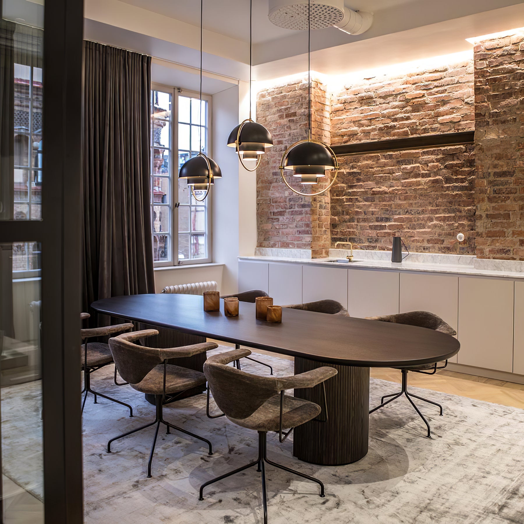 Dark ring pendants over a kitchen island against an exposed brick wall.
