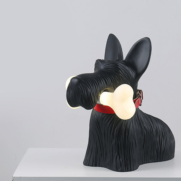 Three-quarter view of the black dog lamp and glowing bone on a white cabinet against a pale wall