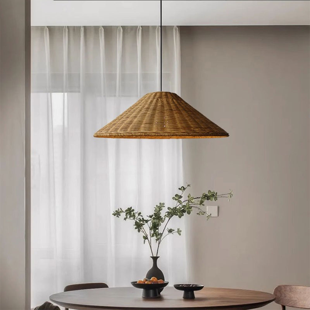 Brown woven rattan cone pendant above a round dining table with a black vase and pale curtains