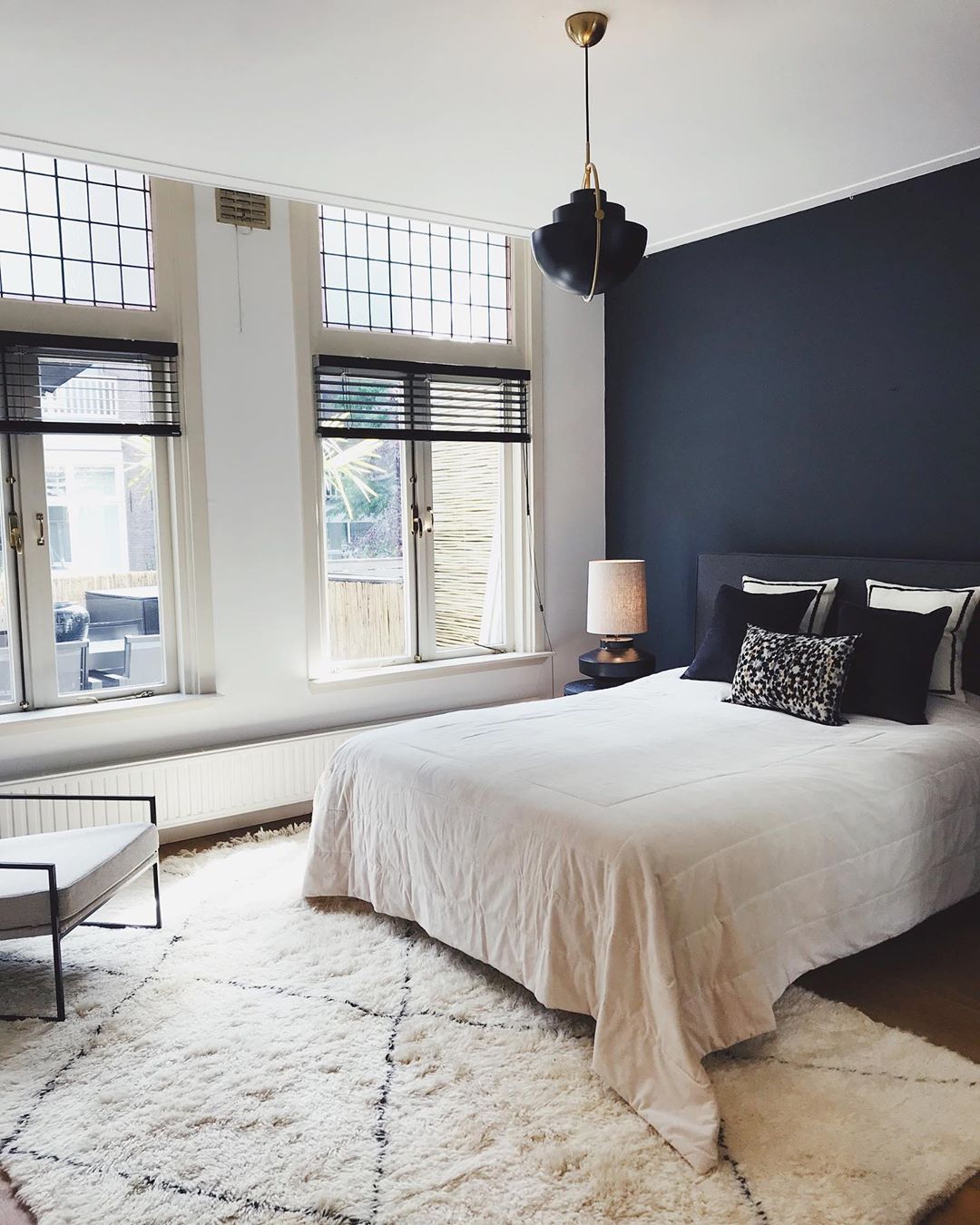 Black open-shade pendant beside tall windows in a bedroom.