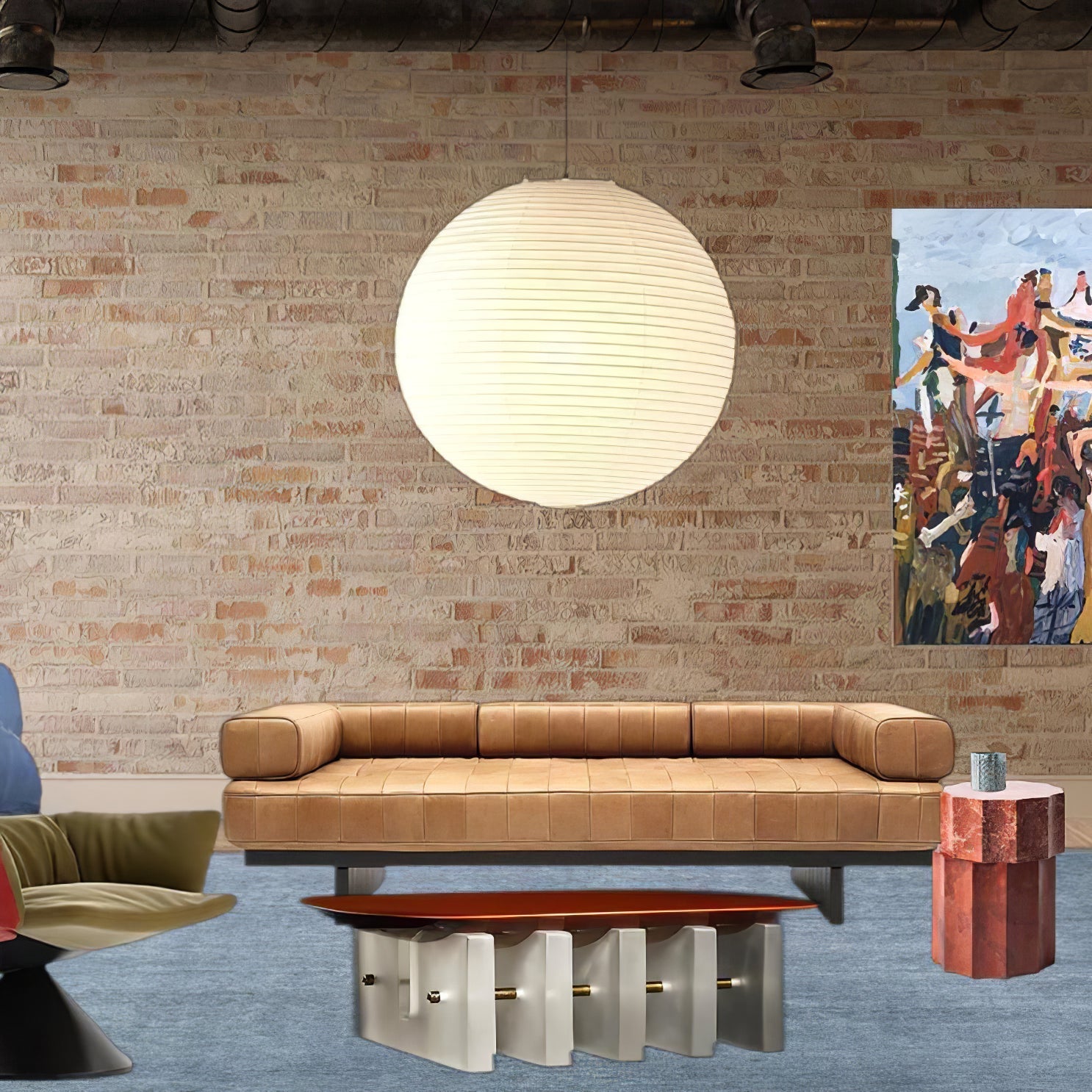 White paper globe above a tan leather sofa against brick wall with colourful art and orange coffee table