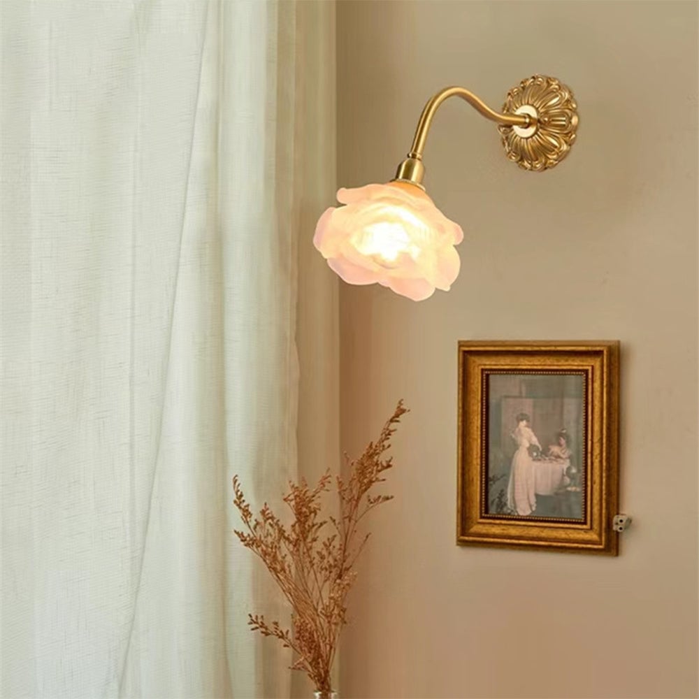 Flower wall light above a framed portrait and dried stems beside a sheer curtain