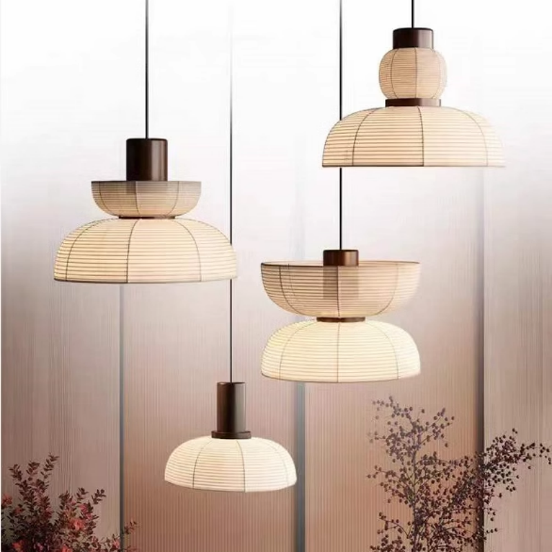 Four ribbed lantern-like pendant shapes in front of a panelled wall and decorative branches