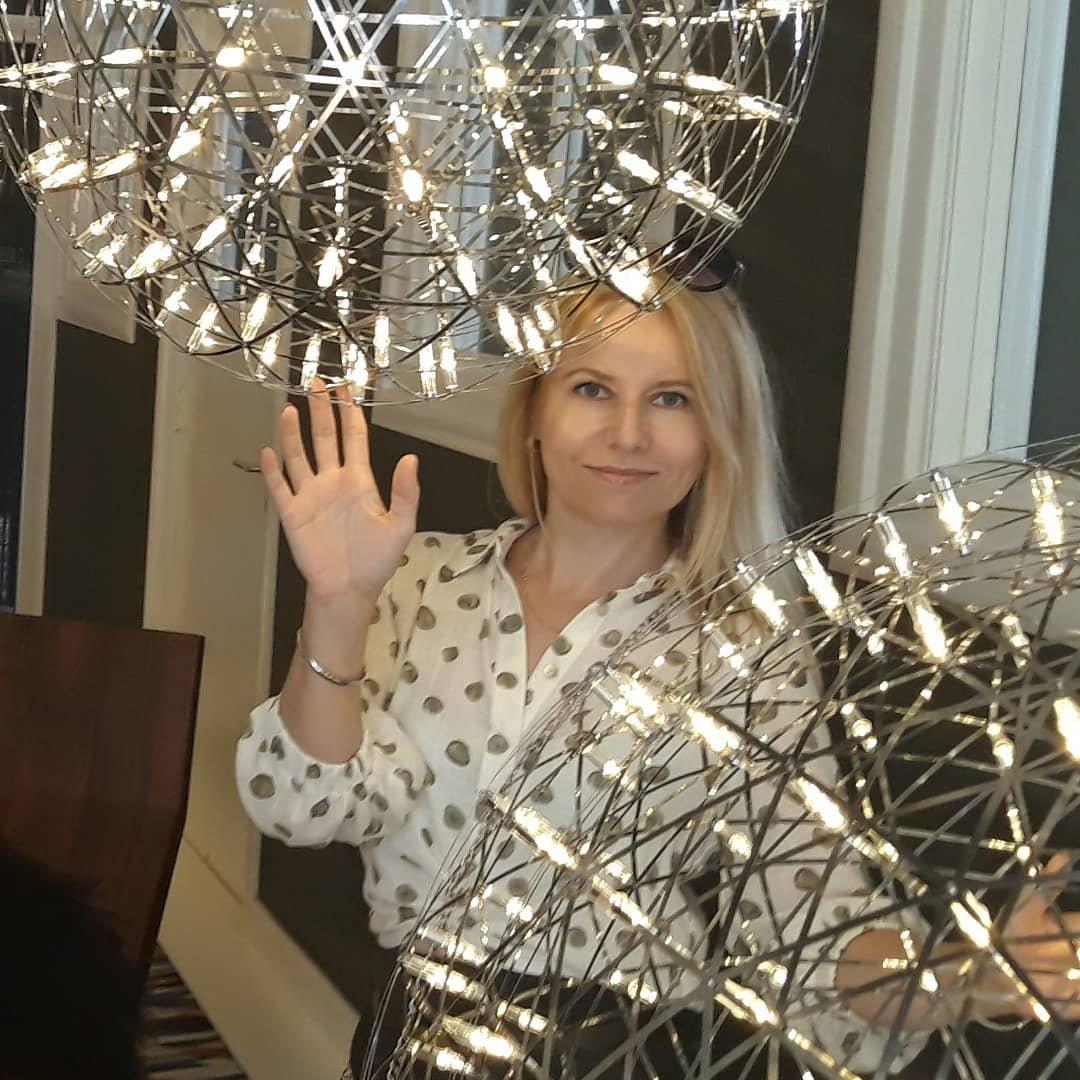 Person reaching upward beside illuminated lattice globes in a display space