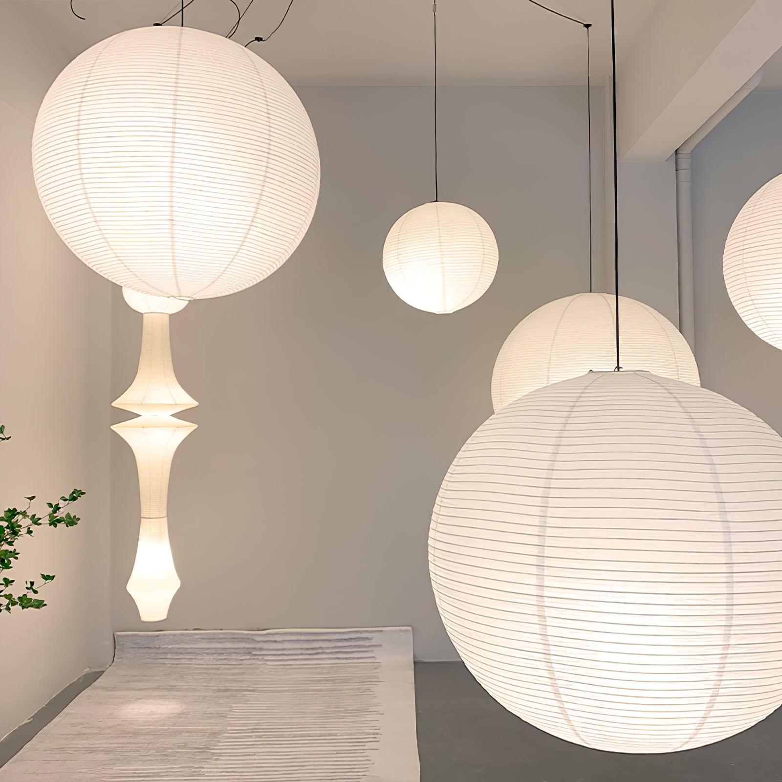 Showroom with large globes, flattened paper shade and a tall waisted pendant among black cords and plants