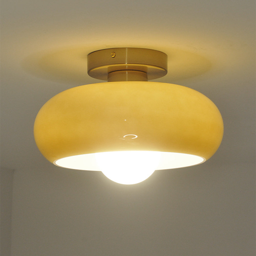 Orange glass ceiling lamp illuminated beneath a gold fitting