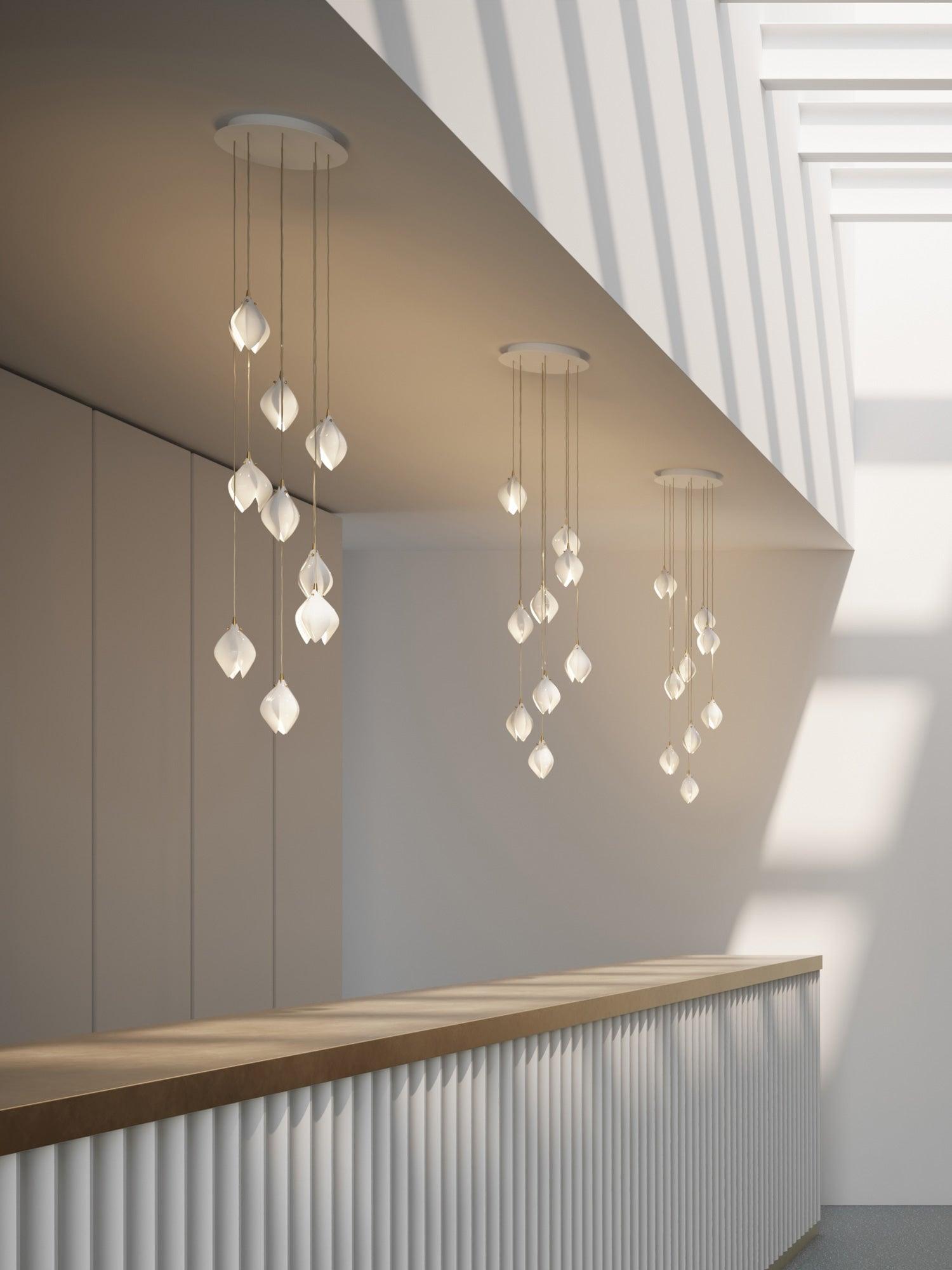 Three white ceiling canopies with petal clusters over a wood-topped fluted counter