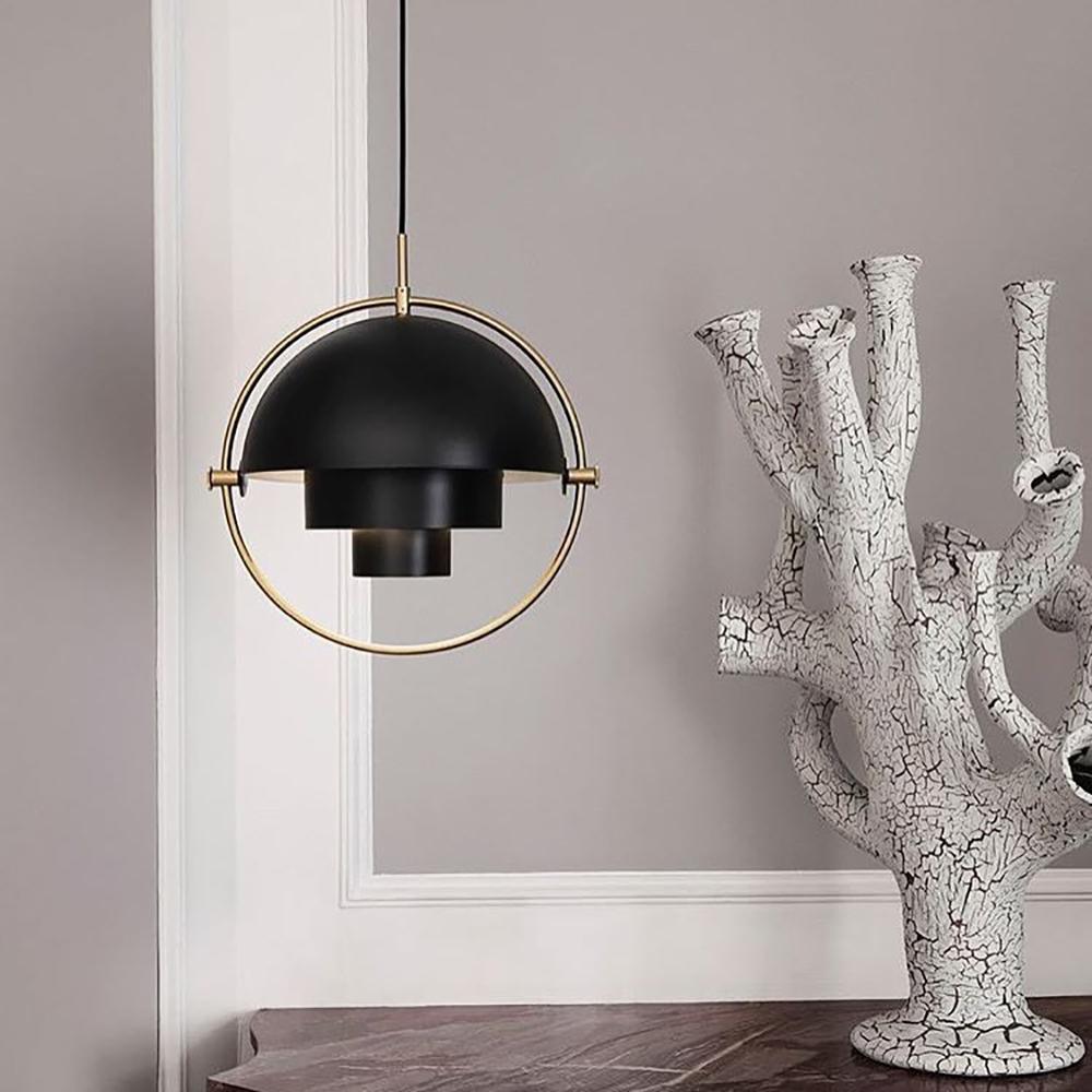 Black dome pendant in a gold-toned ring beside a branch-shaped sculpture.