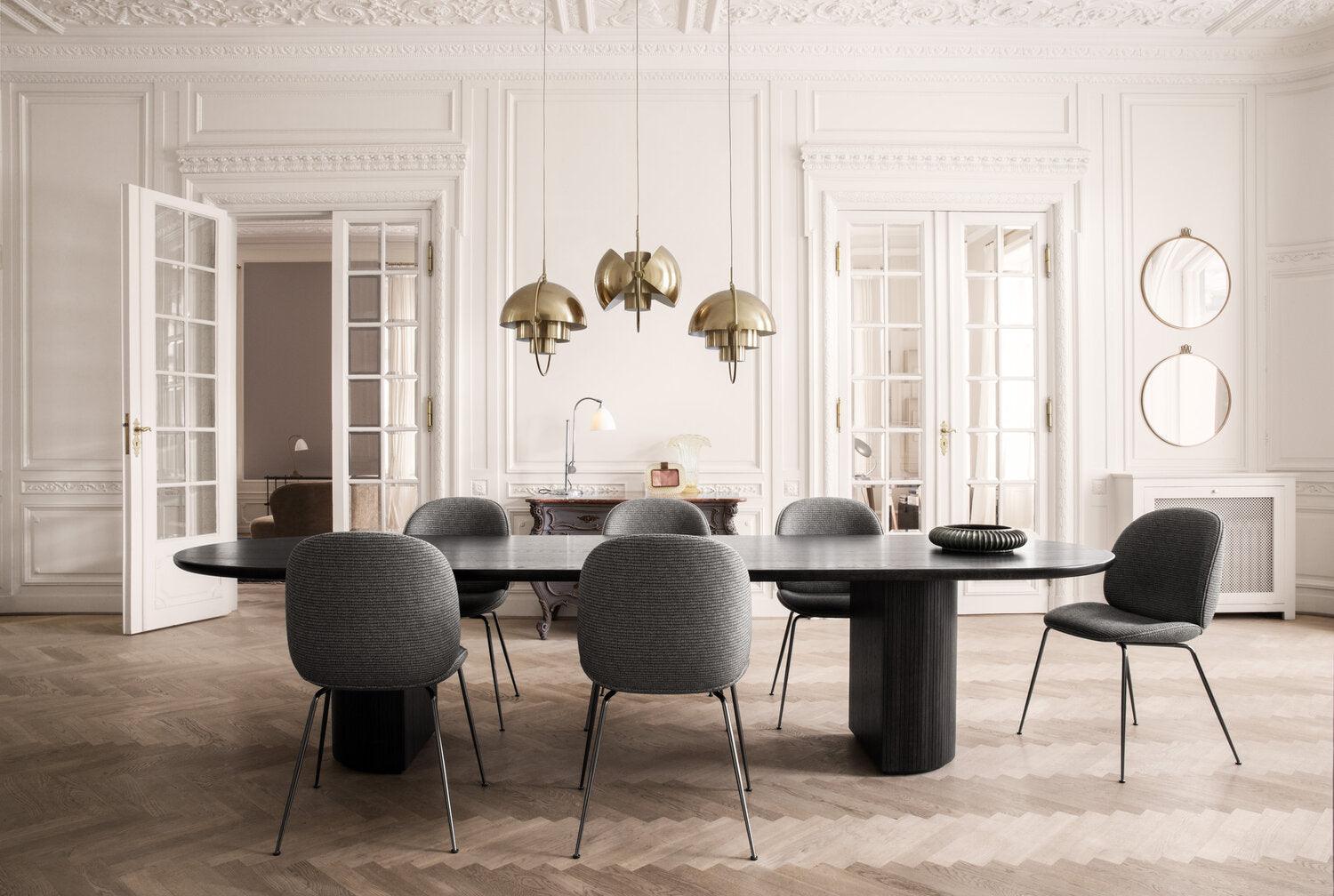 Gold-toned pendants over a long black table surrounded by grey chairs.