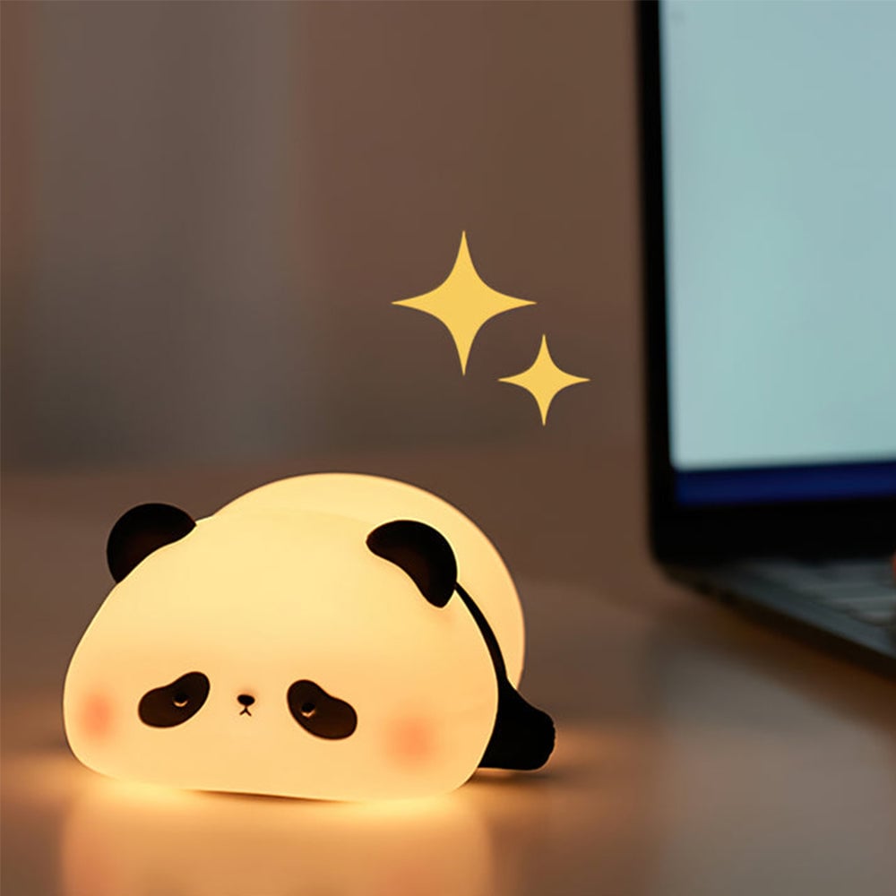 Glowing panda night light on a flat desk beside a laptop screen and keyboard