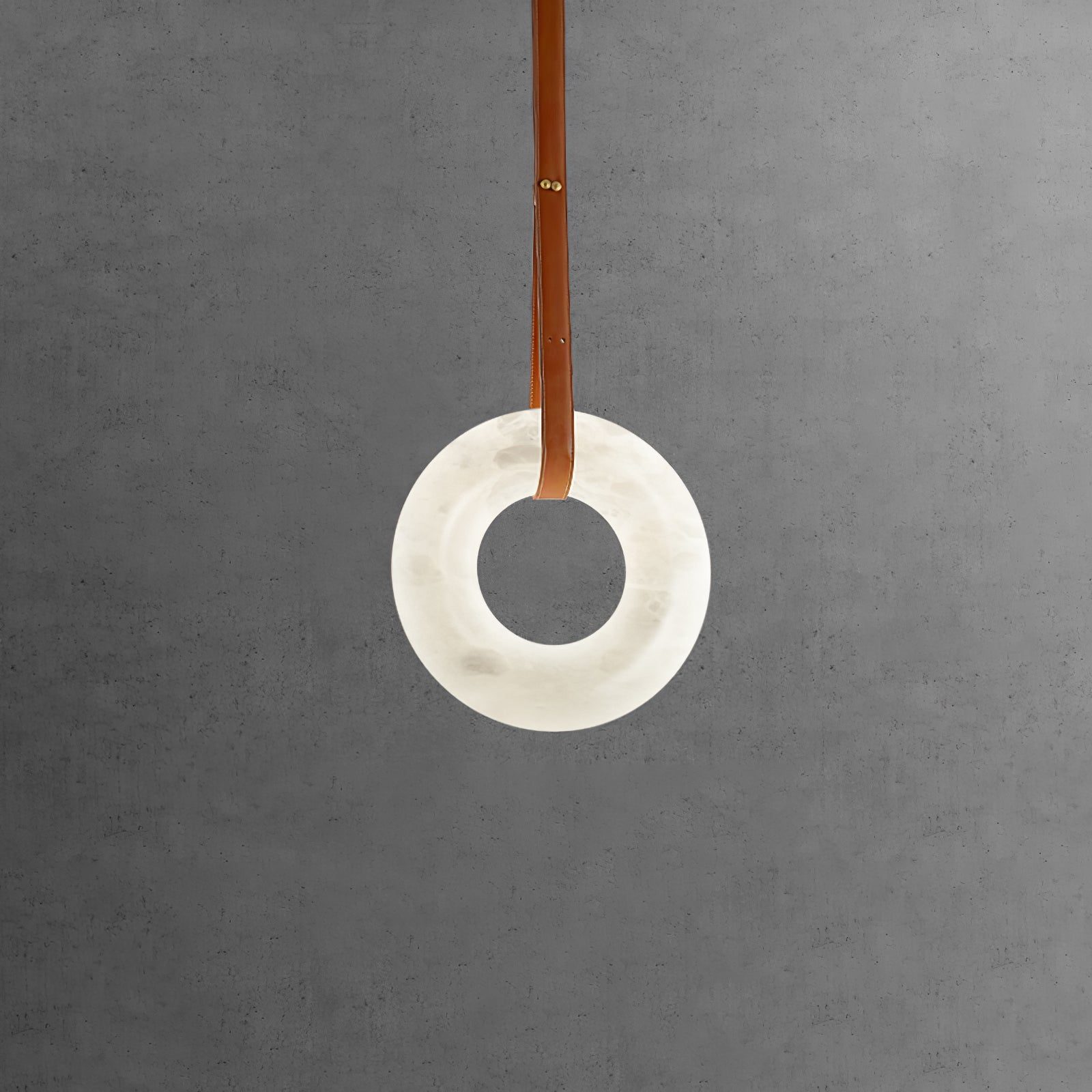 Vertical white alabaster ring on a brown strap against concrete.